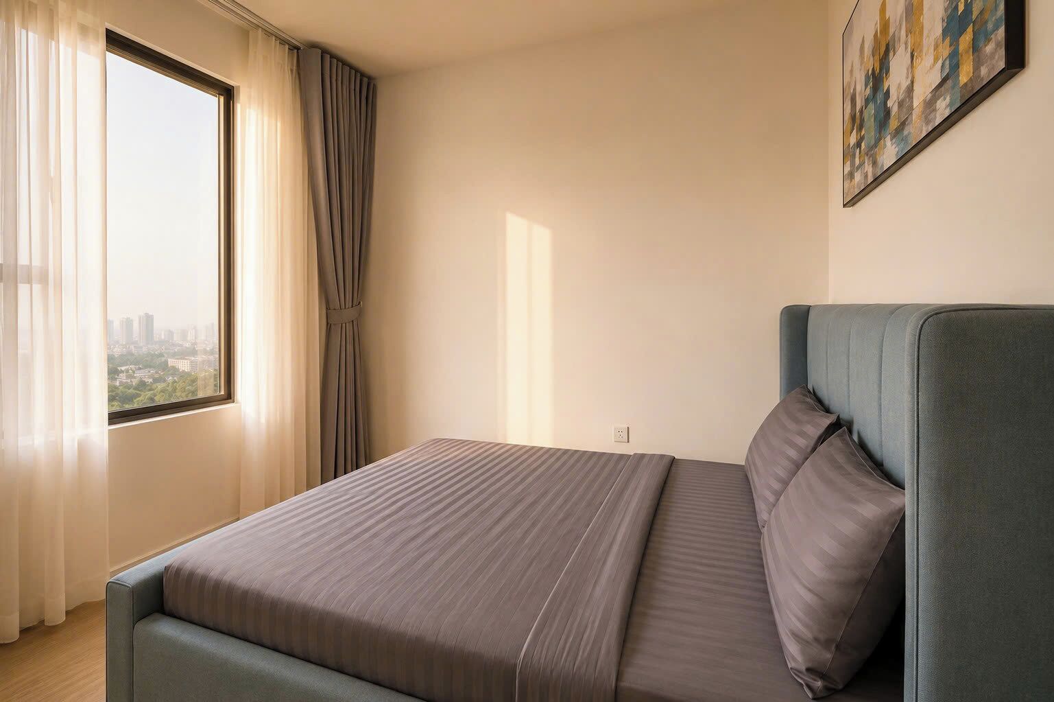 A single bed with a headboard, a window with curtains, and a painting on the wall.