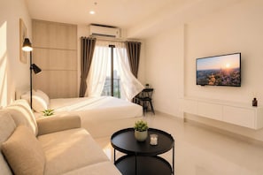 Una habitación de hotel moderna con una cama, un sofá, un televisor y una pequeña mesa con una planta.