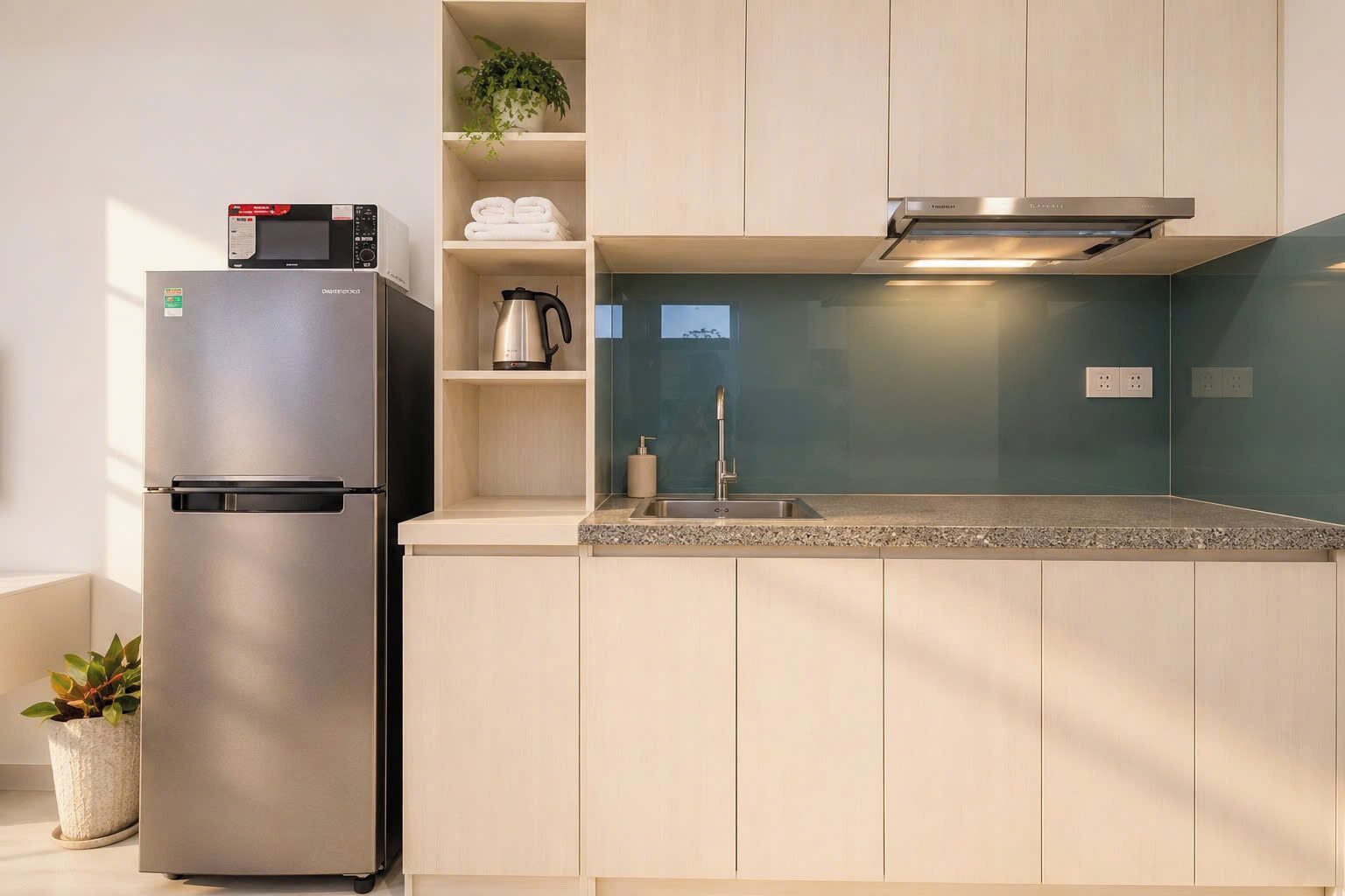 A modern kitchen with a built-in refrigerator, a kettle, and a sink.