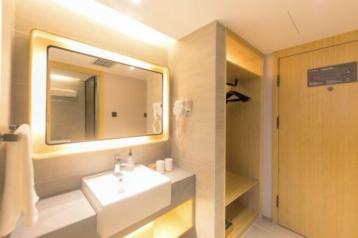 A modern bathroom with a large mirror, a sink, and a shower area.
