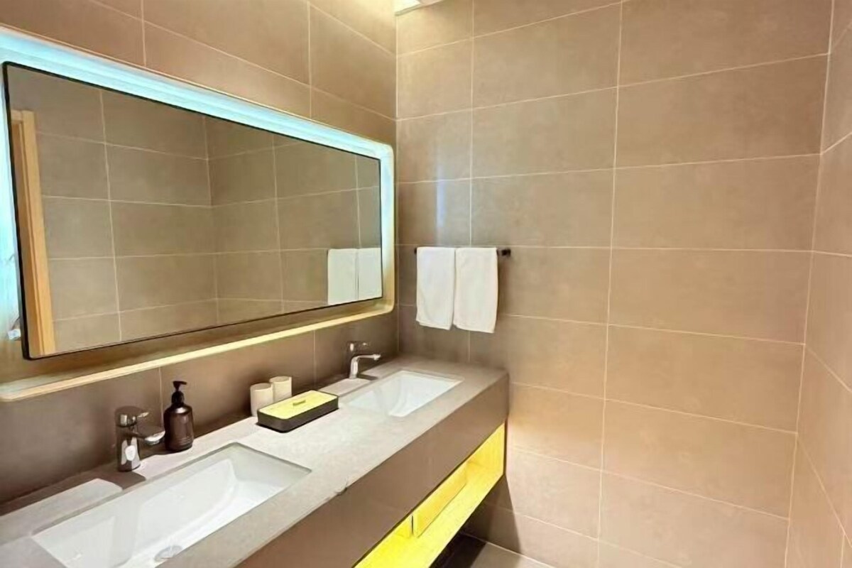 A modern bathroom with two sinks, a large mirror, and a towel rack.