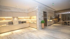 A modern kitchen with marble countertops and built-in appliances, a central island, and a seating area with a view. - JI Hotel (Beijing Shangdi Anningzhuang) (Beijing)