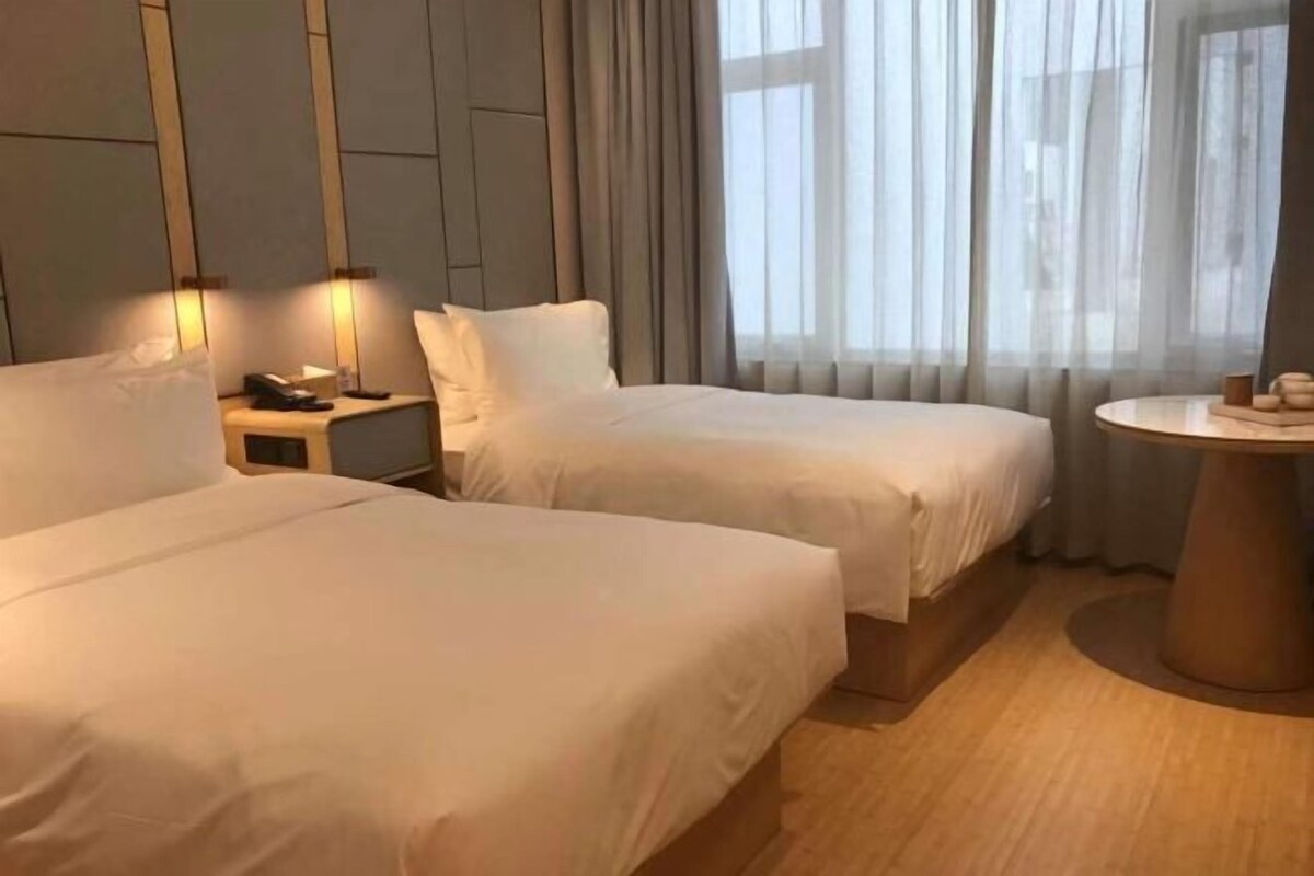A hotel room with two beds, a bedside table with a phone, and a round table with candles.