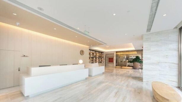 A modern hotel lobby with a reception desk, a seating area, and a bookshelf. - JI Hotel (Beijing Shangdi Anningzhuang) (Beijing)
