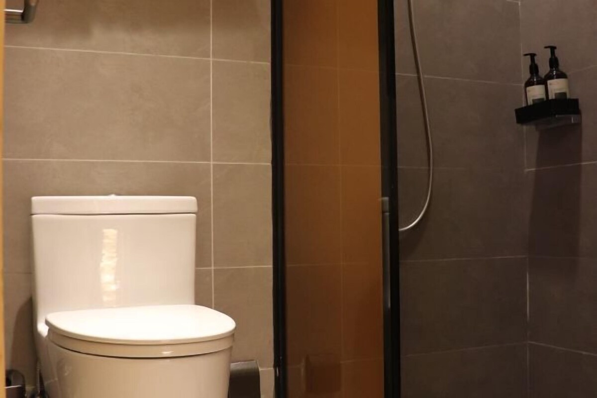 A bathroom with a toilet, a shower area, and a shelf with toiletries.