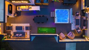 A rooftop pool area with a hot tub, seating, and a mini-golf setup.