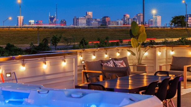 An outdoor seating area with a city skyline view, string lights, and a hot tub.