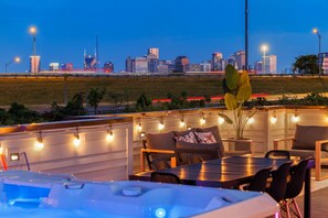 An outdoor seating area with a city skyline view, string lights, and a hot tub. - Luxury NEW Townhome- 9beds -rooftop with private hot tub- game room! (Nashville)