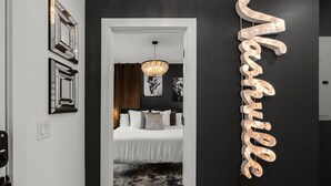 A bedroom with a bed, a chandelier, and a wall with a light-up sign.