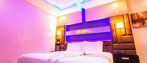 Ein modernes Hotelzimmer mit einem großen Bett, einem Nachttisch und stimmungsvoller Beleuchtung.
