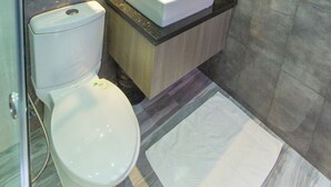 Un baño moderno con inodoro blanco, lavabo y espejo.