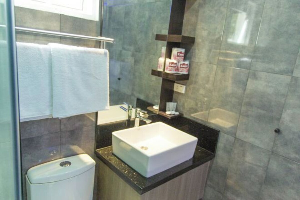A modern bathroom with a white sink, a toilet, and a mirror.