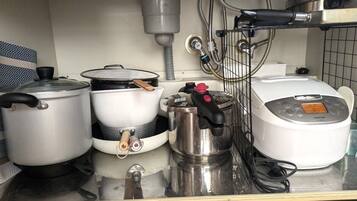 A kitchen counter with various cooking appliances including a rice cooker, pots, and a kettle.