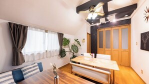 A cozy room with a wooden dining table, bench seating, a ceiling fan, and a large window with curtains. - NOT A HOME Kameari Station 5 min. walk Free parking Disney Haneda Airport bus direct 90m2 Tea ceremony experience (葛飾区)