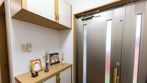 A hotel room with a wooden console table, a framed picture, a vase with flowers, and a wall-mounted light switch. - NOT A HOME Kameari Station 5 min. walk Free parking Disney Haneda Airport bus direct 90m2 Tea ceremony experience (葛飾区)
