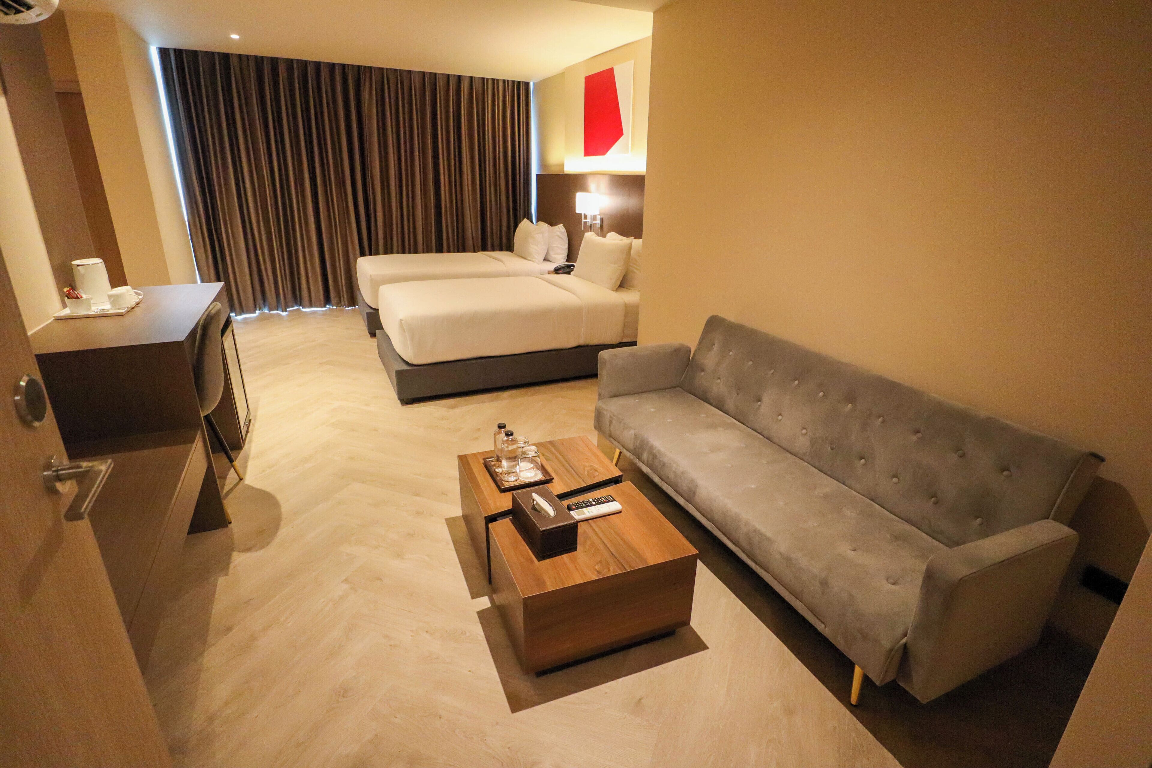 A hotel room with a bed, a sofa, a coffee table, and a desk.