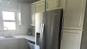 A kitchen with white cabinets, a stainless steel refrigerator, a sink, and a window. - Welcome to The Tennerton House-Charming 2-bedroom with AC and WiFi in Buckhannon (Buckhannon)