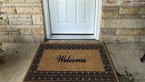 A white door with a decorative glass panel and a doormat that reads "Welcome". - Welcome to The Tennerton House-Charming 2-bedroom with AC and WiFi in Buckhannon (Buckhannon)