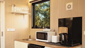 A compact kitchen with a microwave, toaster, coffee maker, and dishwasher. - Rowsley Valley Tiny House 2 by Tiny Away (Glenmore)
