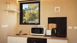 A compact kitchen with a microwave, toaster, and sink. - Rowsley Valley Tiny House 2 by Tiny Away (Glenmore)