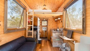 Une petite cabine dotée d’un lit en mezzanine, d’une kitchenette, d’un coin salon et de grandes fenêtres.