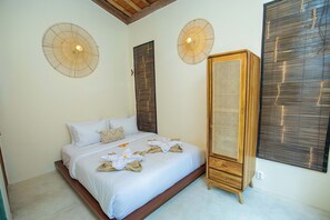 A neatly made bed with white linens and decorative towels, a wooden wardrobe, and two wall-mounted fans. - Sunset House Ceningan (Ceningan Island)