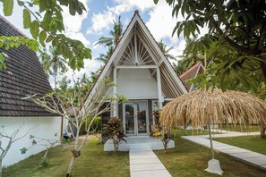 A house with a triangular roof, a thatched roof structure, and a paved pathway leading to the entrance. - Sunset House Ceningan (Ceningan Island)