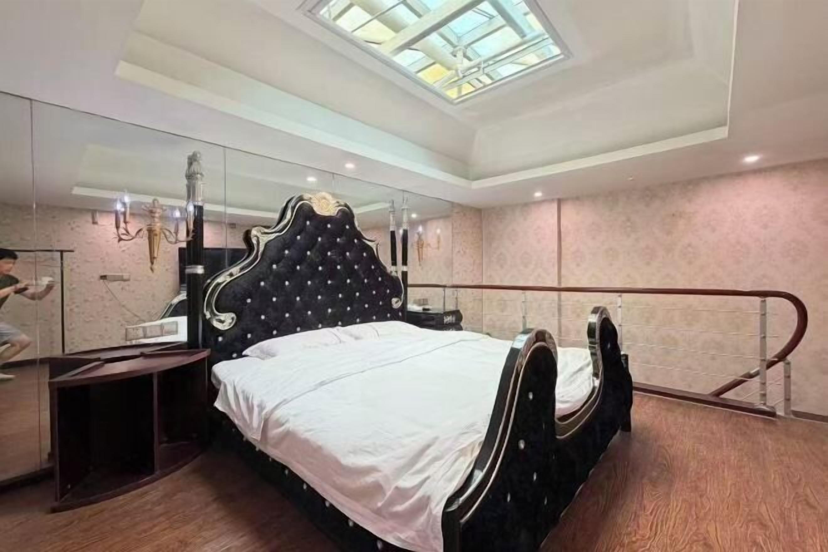 Un dormitorio con una cama grande, un espejo y un tragaluz.