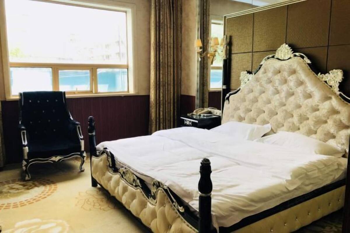 Une chambre d’hôtel avec un grand lit, une chaise, une table de chevet et une fenêtre.