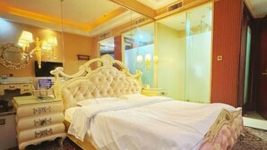 Une chambre à coucher avec un grand lit, une commode, un miroir et un téléviseur.