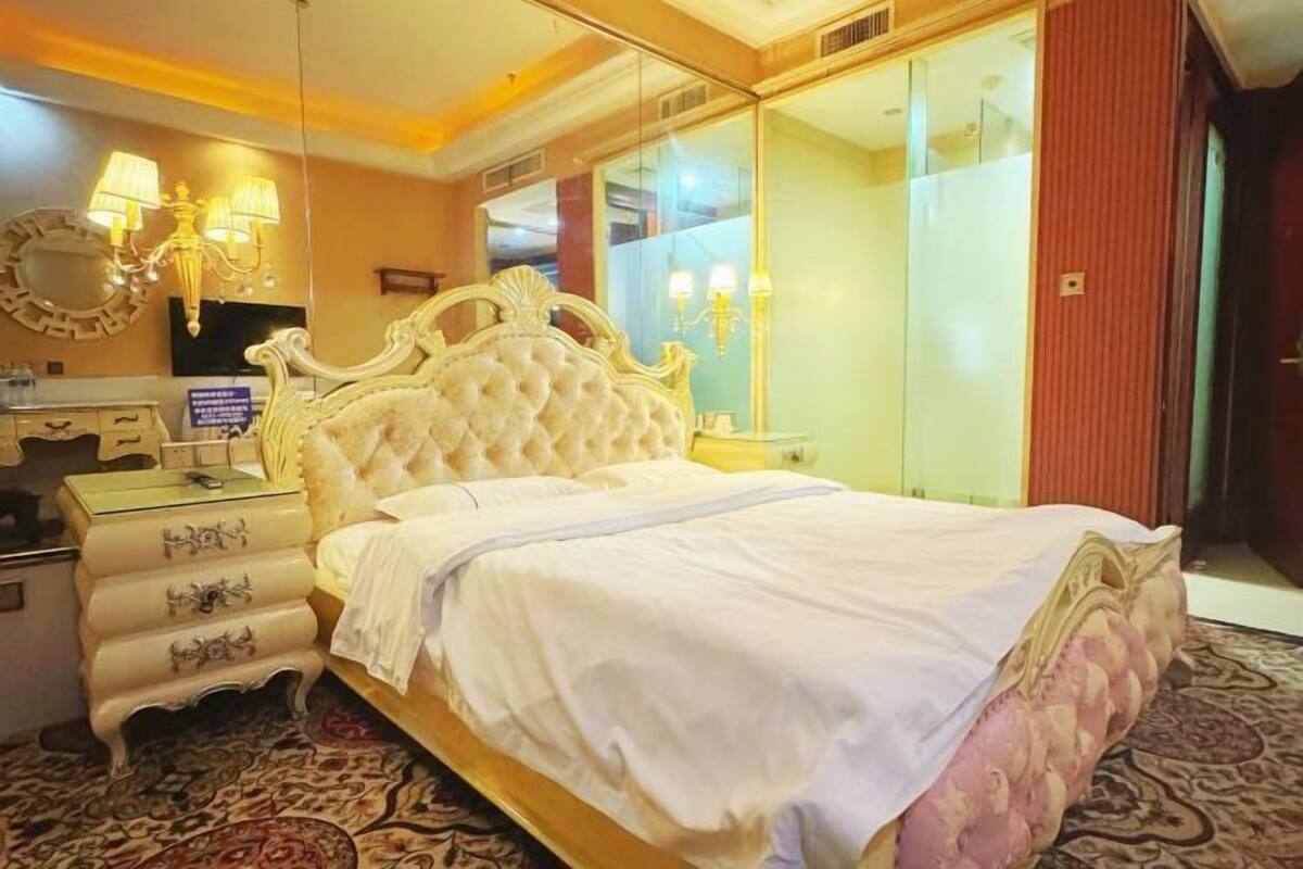 Une chambre à coucher avec un grand lit, une commode, un miroir et un téléviseur.