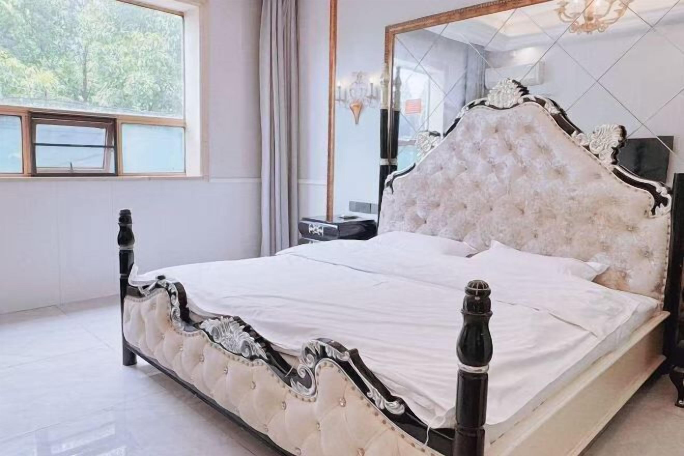 A bed with a tufted headboard, a bedside table, and a nightstand.
