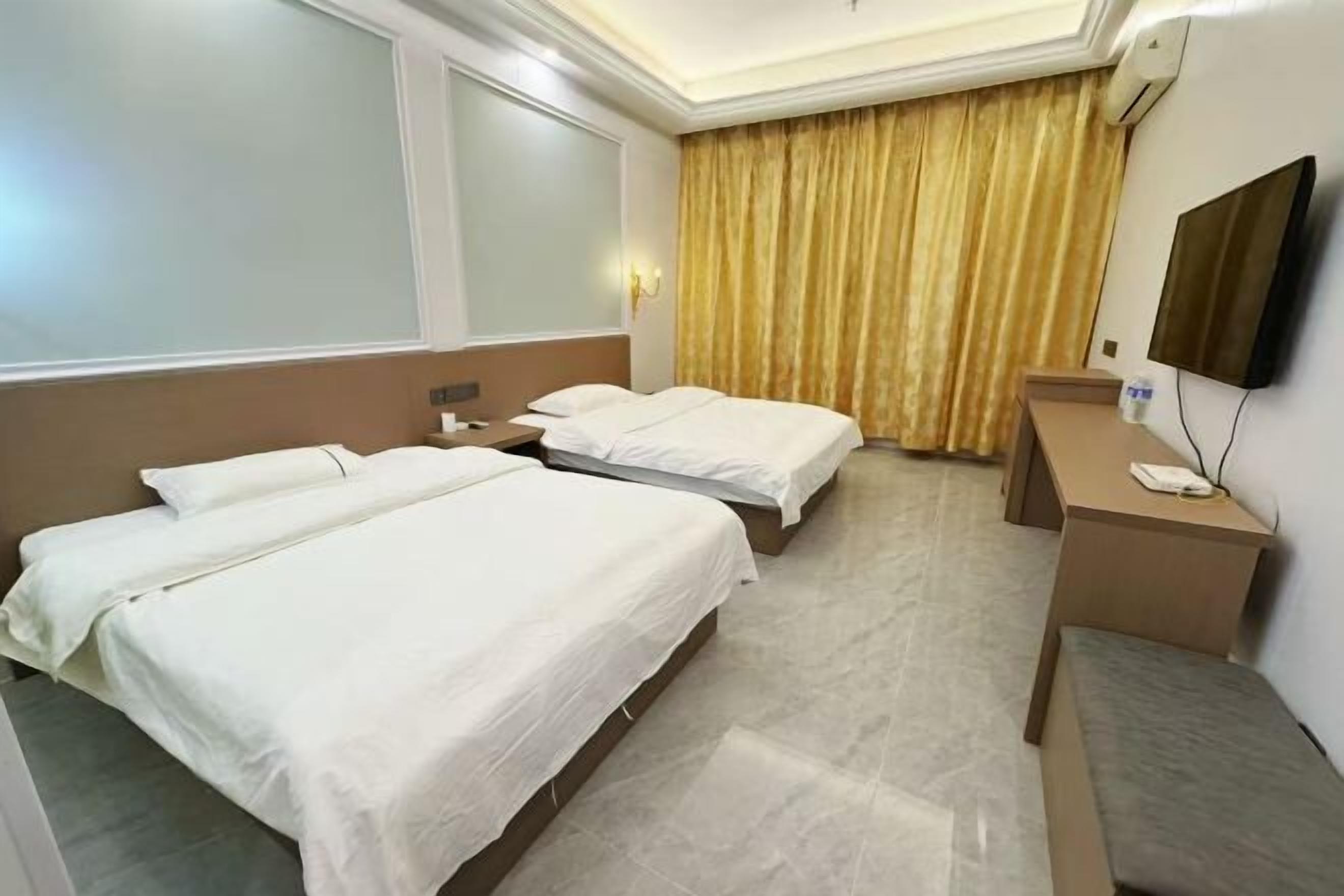 A hotel room with two beds, a desk, a chair, a TV, and a large window with curtains.