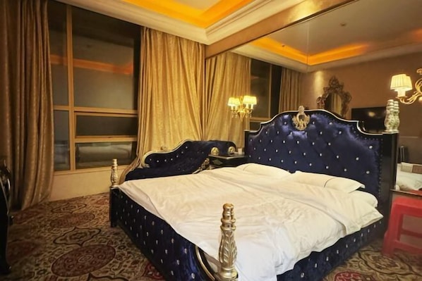 A hotel room with a large bed, a television, a desk, and a chair.