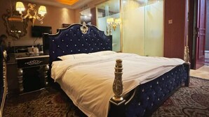 Une chambre à coucher avec un grand lit, une commode, un miroir et un téléviseur.