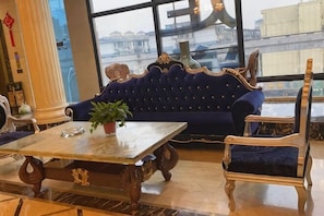 Ein Zimmer mit einem dunkelblauen Sofa, einem Holztisch und einem goldrahmen Sitzmöbel.