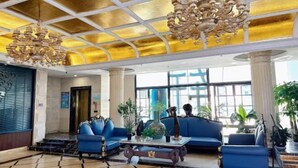 A lobby with blue sofas, a chandelier, and large windows. - Wuhu Vienna Boutique Hotel (Wuhu)