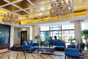 A lobby with blue sofas, a chandelier, and large windows.
