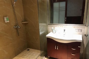 Une salle de bain avec une douche à parois de verre, un lavabo blanc et un meuble en bois doté de tiroirs.