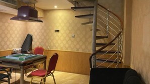 Une pièce équipée d’une table de billard, de chaises, d’un escalier en colimaçon et d’une bouche d’aération au plafond.