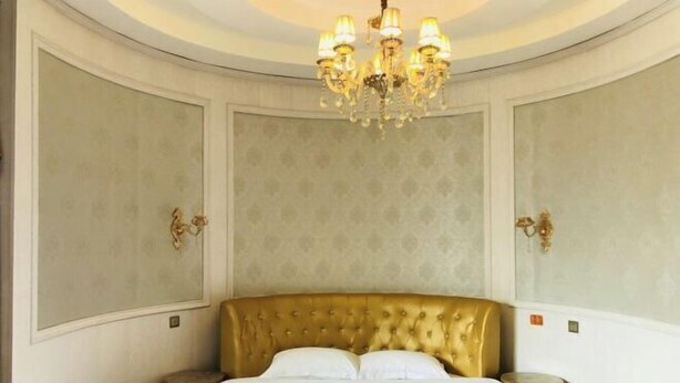 Une chambre dotée d’un grand lit, d’un lustre et d’appliques murales.