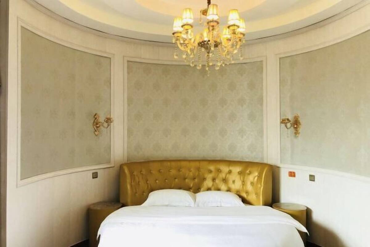 Une chambre dotée d’un grand lit, d’un lustre et d’appliques murales.