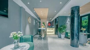 A modern hotel lobby with a reception desk, seating area, and a large pillar. - MILA HOTEL (Shanghai)
