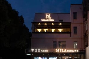 A hotel with a prominent sign, a ground floor entrance, and a second floor balcony. - MILA HOTEL (Shanghai)