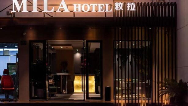 The exterior of the MILA HOTEL with a modern design, featuring a prominent entrance and a reception area visible through the glass doors. - MILA HOTEL (Shanghai)