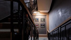 A staircase with a wooden handrail and black metal railings, leading to a landing with framed pictures on the wall. - MILA HOTEL (Shanghai)