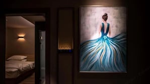 A hotel room with a bed, a wall-mounted light, and a framed painting. - MILA HOTEL (Shanghai)