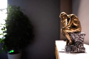 Una statua di una figura seduta su un piedistallo.