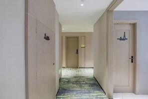 A hotel corridor with a patterned carpet, wooden doors, and a light-colored wall. - MILA HOTEL (Shanghai)