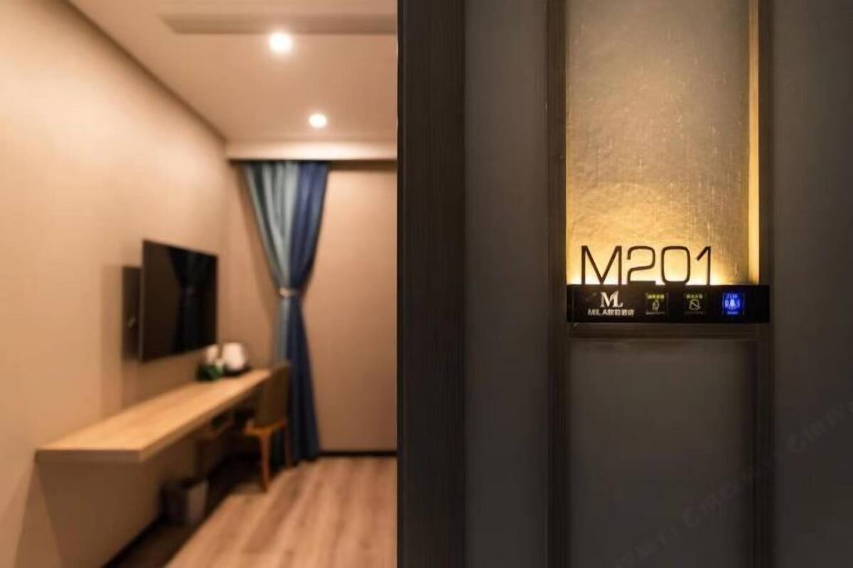 Et hotelværelse med skrivebord, stol og fjernsyn.